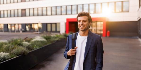 Feierabendstimmung: Ein Mitarbeiter auf dem Heimweg. Die Abendsonne spiegelt sich im Hintergrund auf der Fassade eines Kaufland-Bürogebäudes.