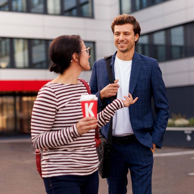 Mitarbeiterin und Mitarbeiter vor einem Kaufland-Bürogebäude im Gespräch.