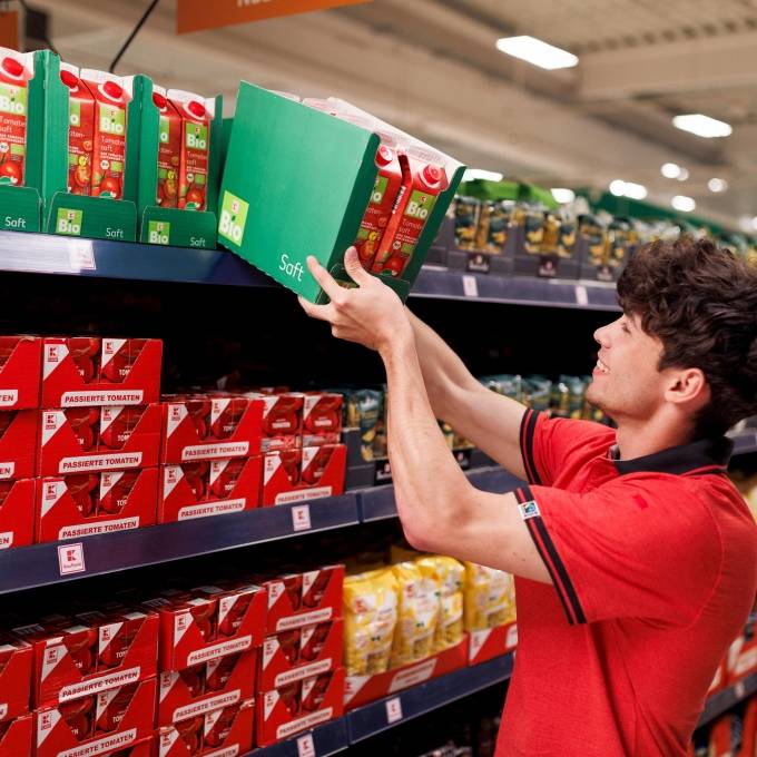 Regalpflege: Ein Schüler in roter Kaufland-Kleidung räumt Ware in Regale ein.