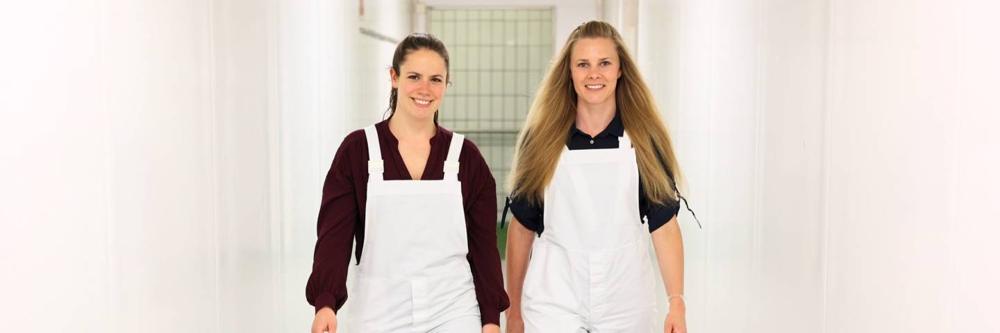 Zwei Kolleginnen aus dem Fleischwerk bei Kaufland laufen einen Gang entlang.