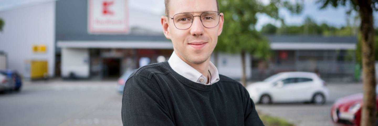 Hausleiter bei Kaufland steht mit verschränkten Armen vor einer Filiale.