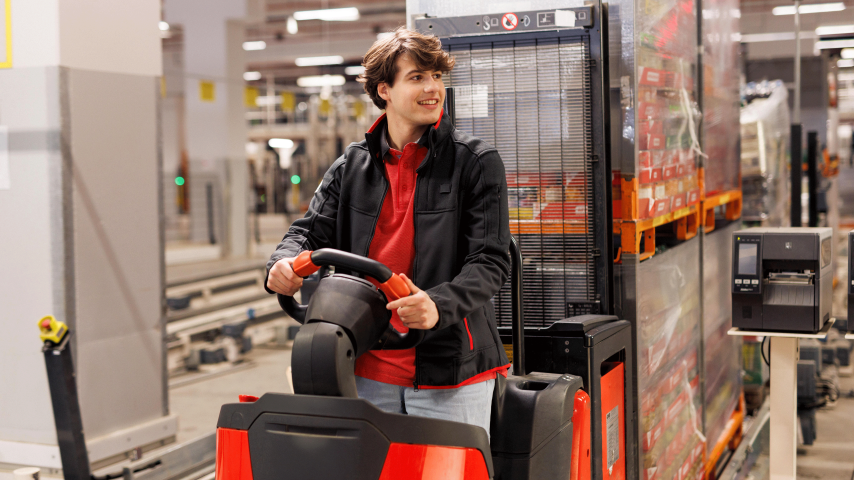 Ein Azubi bedient ein Flurförderfahrzeug im Logistik-Lager.