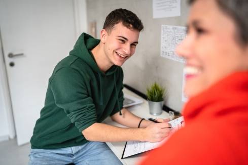 Mutter und Sohn machen sich Notizen am Schreibtisch für eine Bewerbung