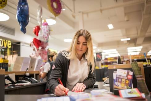 Hausleiterin unterschreibt ein Dokument an der Information einer Kaufland-Filiale.