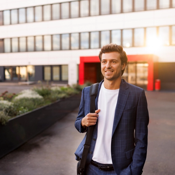 Feierabendstimmung: Ein Mitarbeiter auf dem Heimweg. Die Abendsonne spiegelt sich im Hintergrund auf der Fassade eines Kaufland-Bürogebäudes.