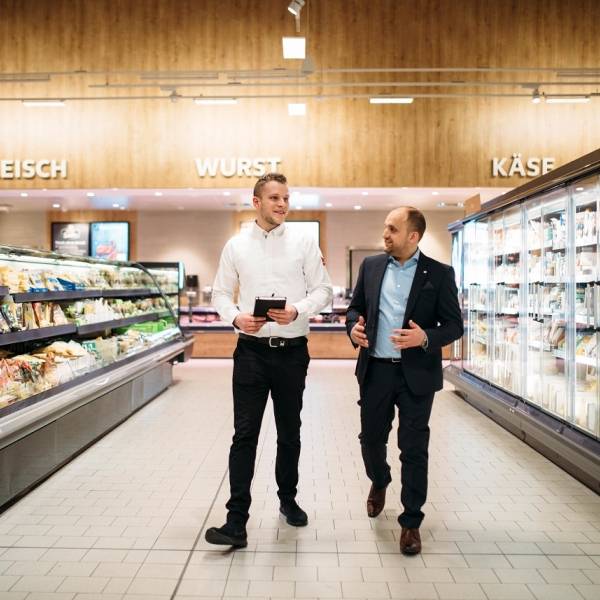 2 leitende Verkaufsangestellte von Kaufland beim Gespräch im Warengang.