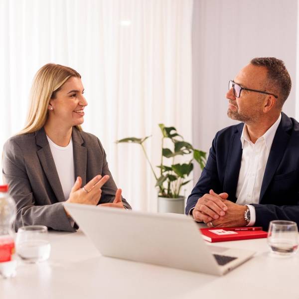 Kandidatin mit Kaufland-Mitarbeiter in einem Konferenzraum der Zentrale beim Bewerbungsgespräch. Auf dem Tisch steht ein aufgeklappter Laptop.