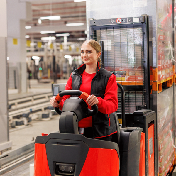 Eine Azubi bedient ein Flurförderfahrzeug im Logistik-Lager.