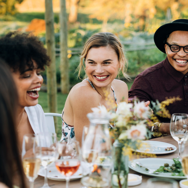 Mehrere Menschen sitzen zusammen in einem Besen am Tisch und lachen.