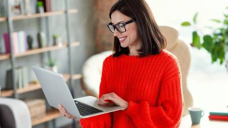 Frau arbeitet mobil von einem Café aus an ihrem Laptop.