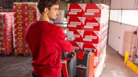 Logistikmitarbeiter von Kaufland rangiert mit einem Hubwagen Palettenware.