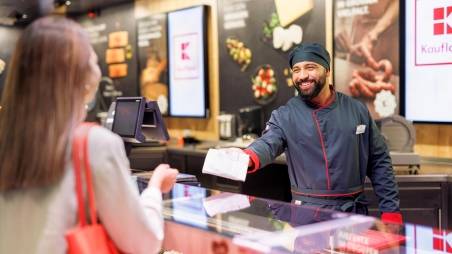 An der Bedientheke einer Kaufland-Filiale: Mitarbeiter in der Fleisch- und Wurstabteilung überreicht der Kundin ihre Bestellung.