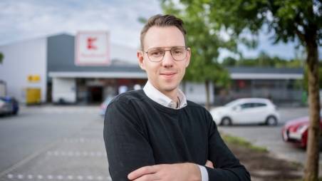 Hausleiter bei Kaufland steht mit verschränkten Armen vor einer Filiale.