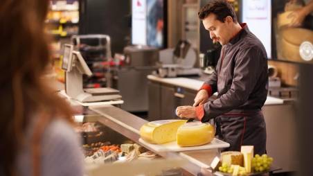 Kaufland-Bedientheke: Ein Verkaufsmitarbeiter schneidet einen Laib Käse auf.