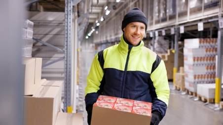 Engagierter Kaufland Logistik Mitarbeiter transportiert Kartons in einem modernen Tiefkühllager. Werde Teil des Kaufland Logistik Teams.