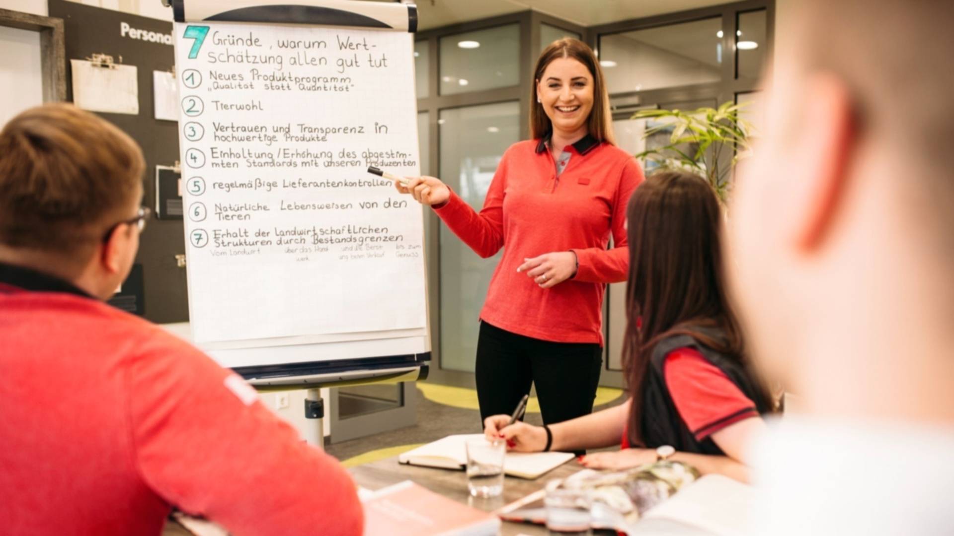 Kaufland Filial-Mitarbeiter bei einer Schulung in einem Besprechungsraum. In der Mitte steht ein Flipchart.