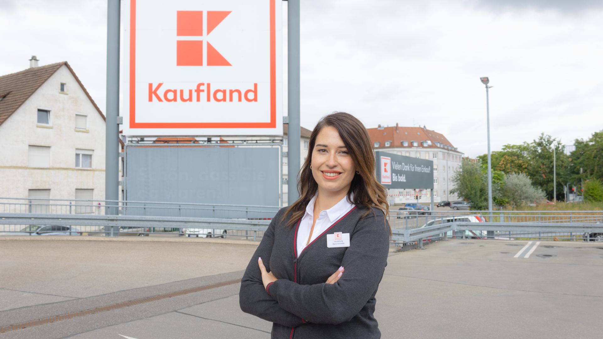 Hausleiterin und ehemalige Trainee steht vor Kaufland-Filiale und lächelt in die Kamera.